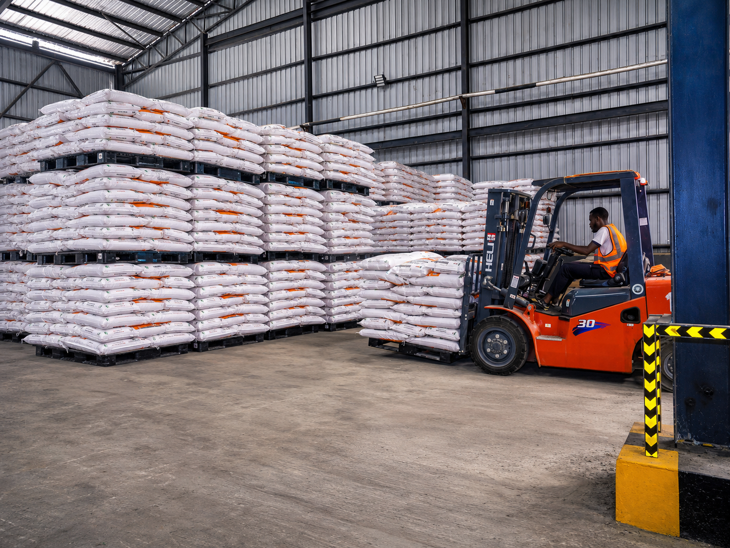 Forklift moving stacked feed sacks inside the TMDK warehouse