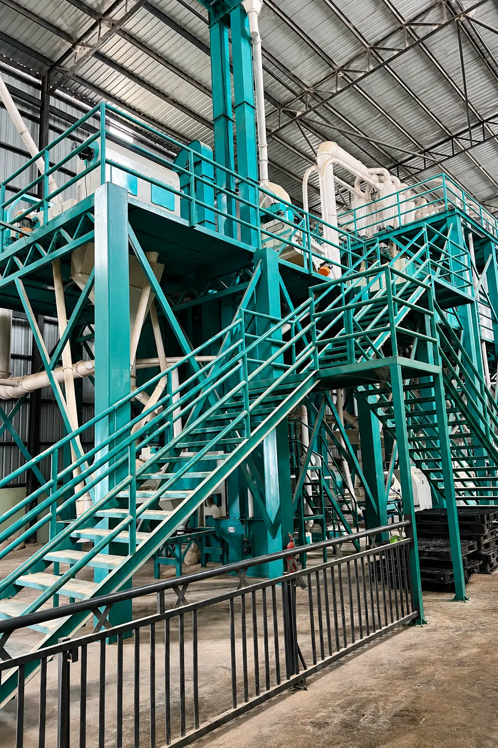 Teal-framed corn milling plant with multi-level platforms and stairways